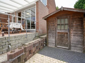 A wooden cabin with a large window and a door, adjacent to a brick building with a glass door. - Stay With Garden, Limburg (Kerkrade)