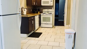 A compact kitchen with a refrigerator, microwave, stove, and sink.