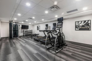 Un gimnasio con cintas de correr, máquinas de pesas y una pantalla de televisión.