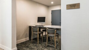 Een bedrijfsruimte met een bureau, twee stoelen, een computer en een bord dat de functie van de ruimte aangeeft.