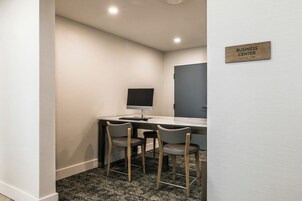 Un centro de negocios con escritorio, dos sillas, computadora y un cartel que indica el propósito de la sala.