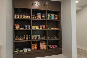 Un garde-manger avec des étagères remplies de divers produits alimentaires, notamment des pâtes, des chips et des en-cas.