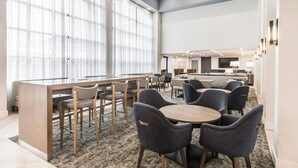 A modern hotel lobby with a bar area, seating arrangements, and large windows.