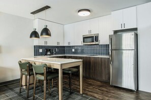 Une cuisine moderne équipée d’une table à manger, de chaises, d’un four à micro-ondes et d’un réfrigérateur.