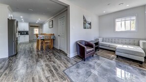 A spacious living area with a grey sofa, a dark armchair, and a dining table with chairs. - 3 bedroom house near scugog lake (Caesarea)
