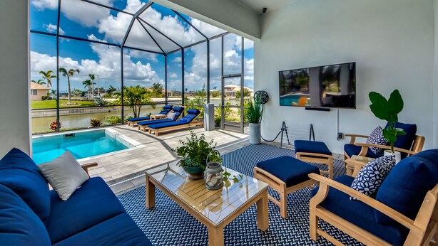 Ein geräumiges Zimmer mit einer großen Glaswand mit Blick auf einen Swimmingpool und einen strahlend blauen Himmel.