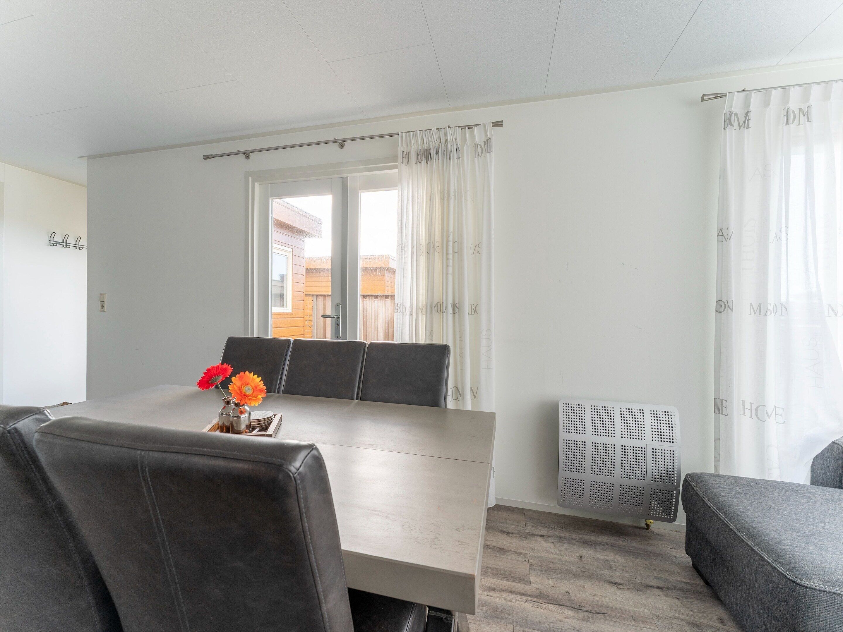 A modern dining area with a table, chairs, and a flower vase.