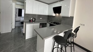 Una cocina moderna con armarios blancos, una isla central con taburetes y una estufa empotrada.