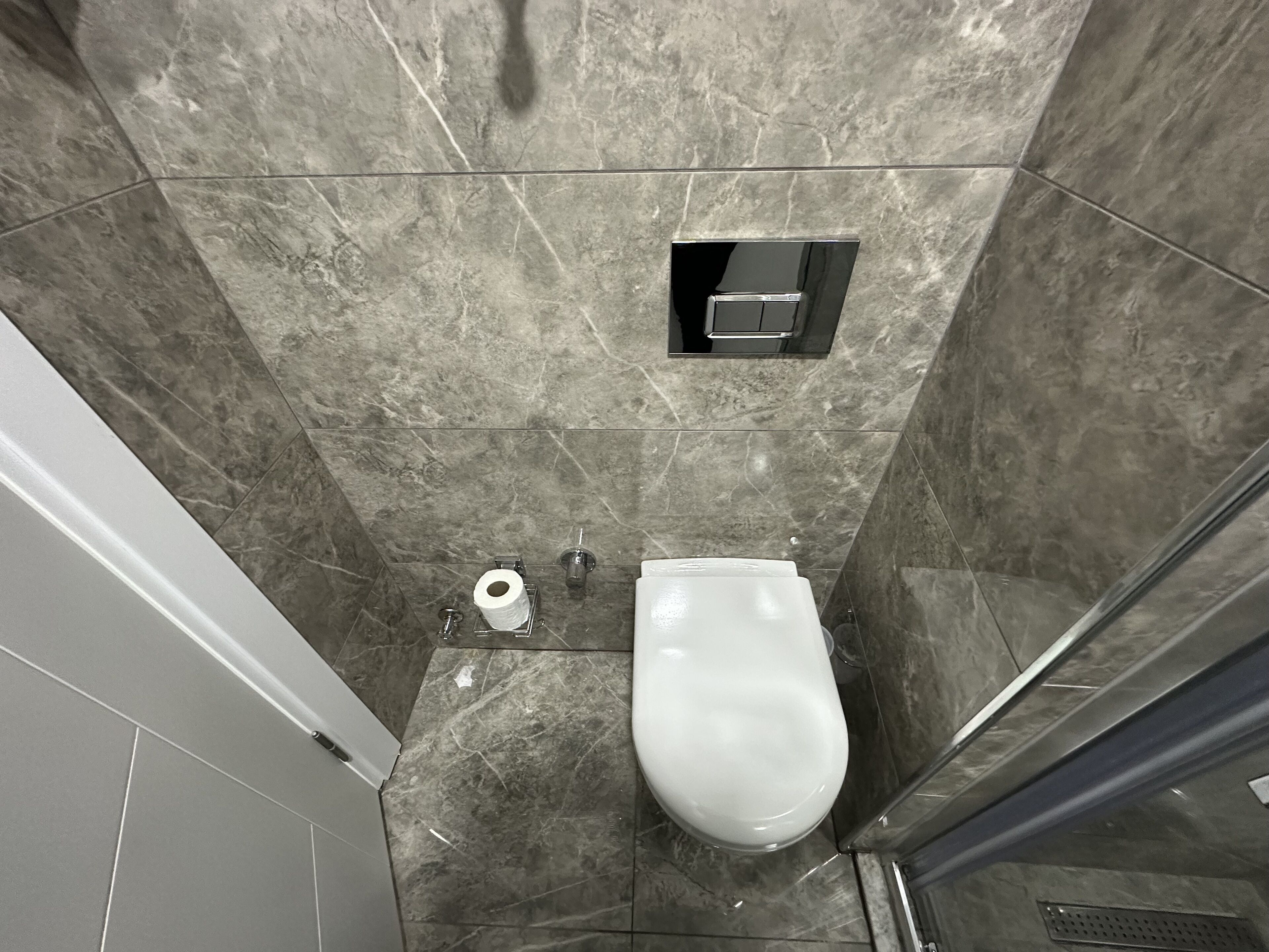 Une salle de bain équipée de toilettes, d’un distributeur d’essuie-tout et d’un espace douche.