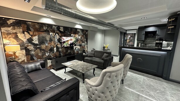 Una sala moderna con pared de piedra, un sofá, una mesa de centro y un sillón.