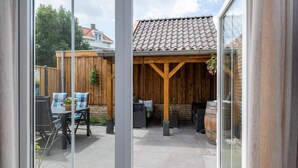 Een terras met een tafel en stoelen, een hangplant en een bakstenen muur.