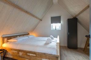 Een slaapkamer met een houten bed, een raam met uitzicht en een zwarte garderobe.