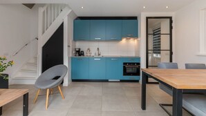 Een moderne keuken met blauwe kastjes, een houten eettafel en een grijze stoel.