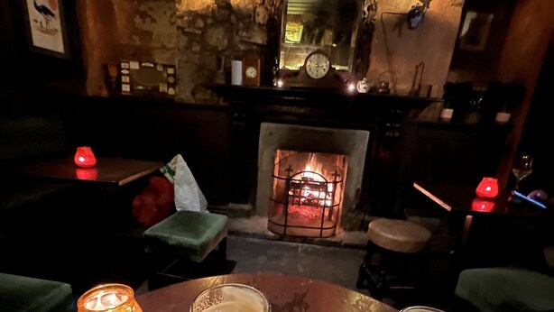 A cozy bar area with a fireplace, two glasses of beer, and a lit candle on a wooden table. - Ennis, 4 minute walk to Downtown (Ennis)