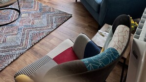 A living room with a blue sofa, yellow cushions, a patterned rug, and a view of a garden through large windows. - Ennis, 4 minute walk to Downtown (Ennis)