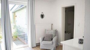 A room with a grey armchair, a white radiator, and a door leading to another room.