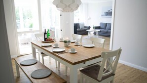 A dining area with a wooden table set for four, white chairs, and a bench.