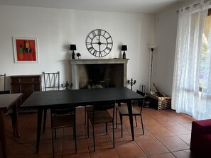 Ein Esszimmer mit Kamin, einer großen Wanduhr und einem gerahmten Kunstwerk.