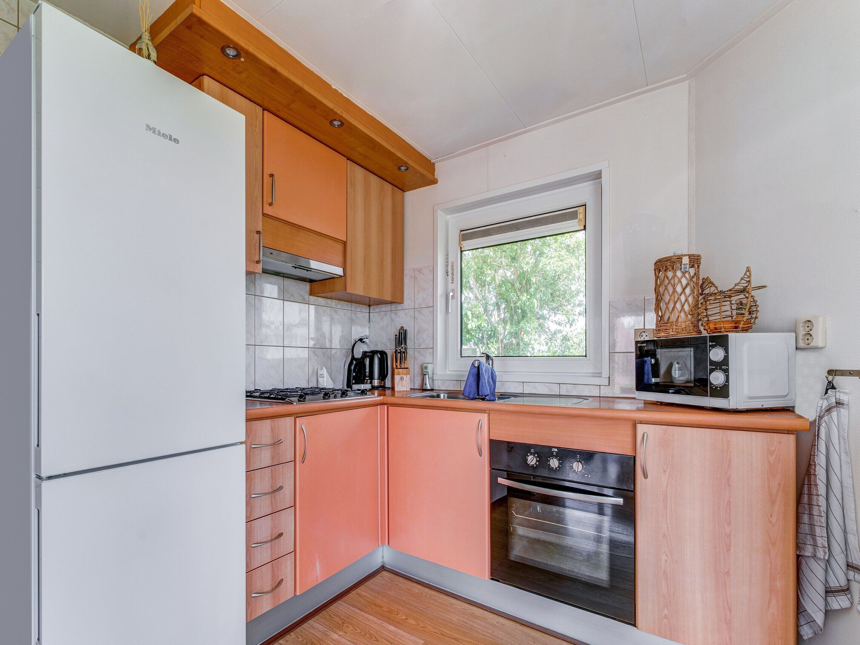 Una cocina compacta con refrigerador, estufa, horno y microondas.