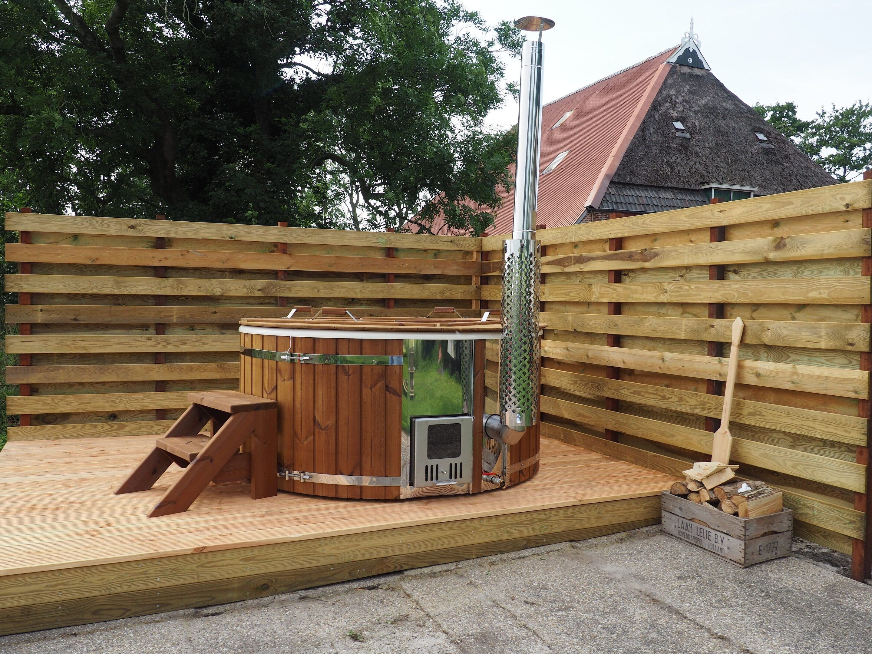 Una terraza de madera con un jacuzzi, una escalera y un pozo de fuego.