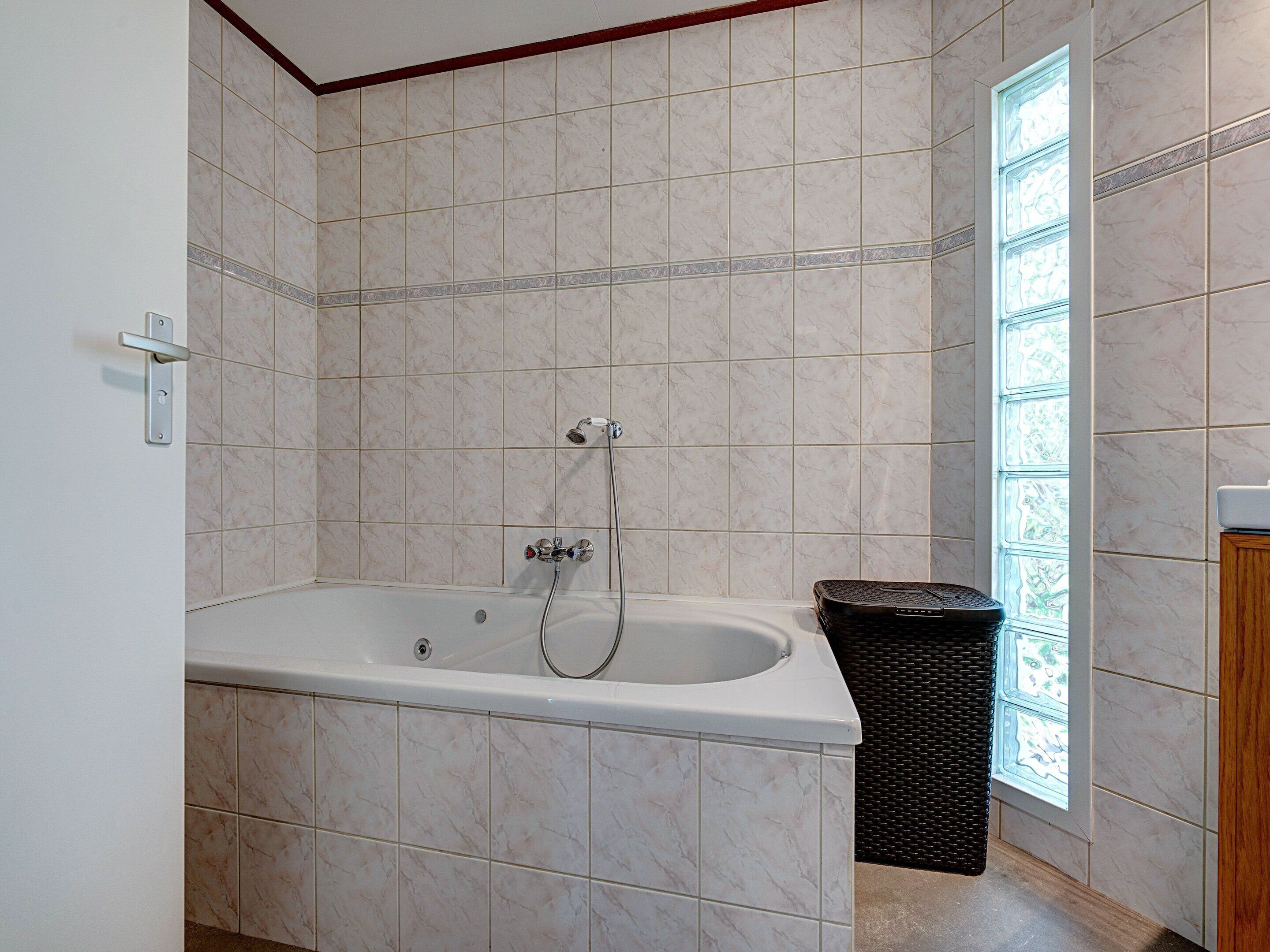 A bathroom with a bathtub, a shower, and a window.