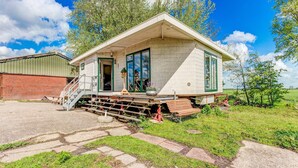 A single-story house with a front porch, a staircase leading to the entrance, and a small garden area. - Farmhouse in Suwald With Hot Tub (Suwâld)
