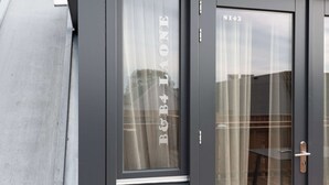 En modern byggnadsfasad med en mörkfärgad dörr som har skylten ”B&B LAONE” och numret ”S142”.