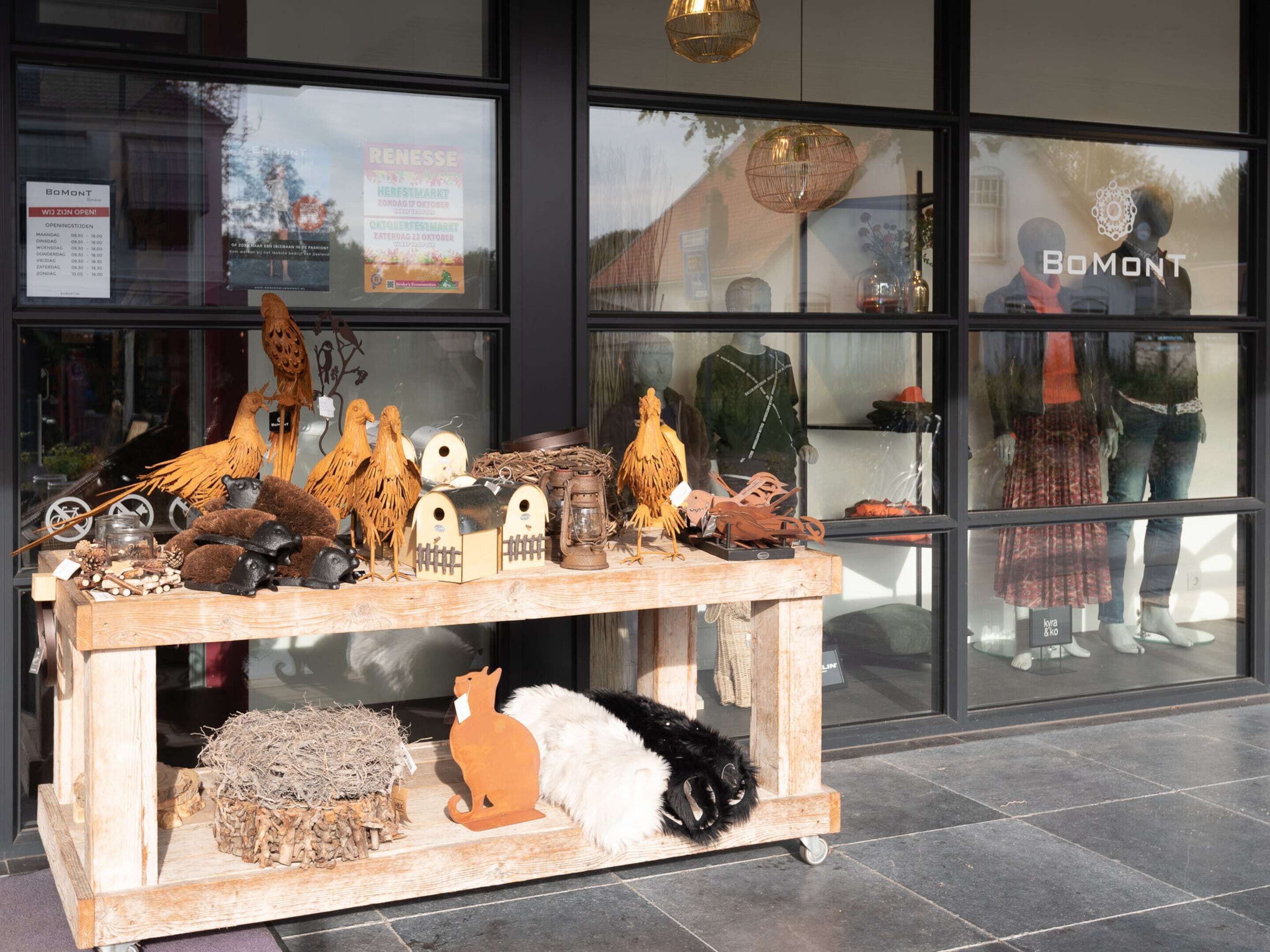 A display of wooden animal figures and a small table outside a store with large windows.