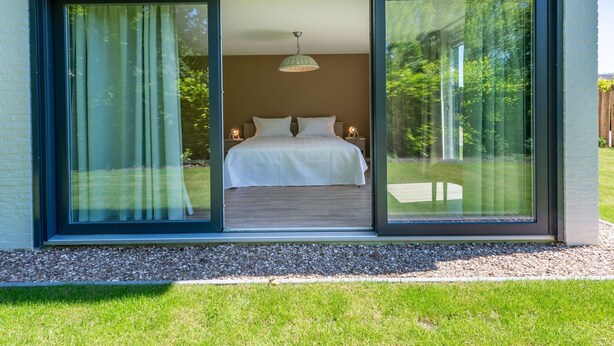 A modern bedroom with a large sliding glass door leading to a grassy area. - Lovely Holiday Home in a Quiet Location (Kamperland)