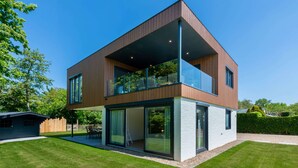 A modern two-story house with large glass windows and a balcony. - Lovely Holiday Home in a Quiet Location (Kamperland)
