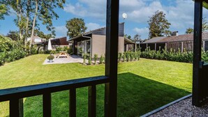 Ein Wohnhaus mit gepflegtem Rasen, einer Terrassenanlage mit Gartenmöbeln und einer Satellitenschüssel.
