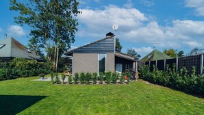 Ein modernes Haus mit Satellitenschüssel, einem gepflegten Rasen und einem kleinen Garten.