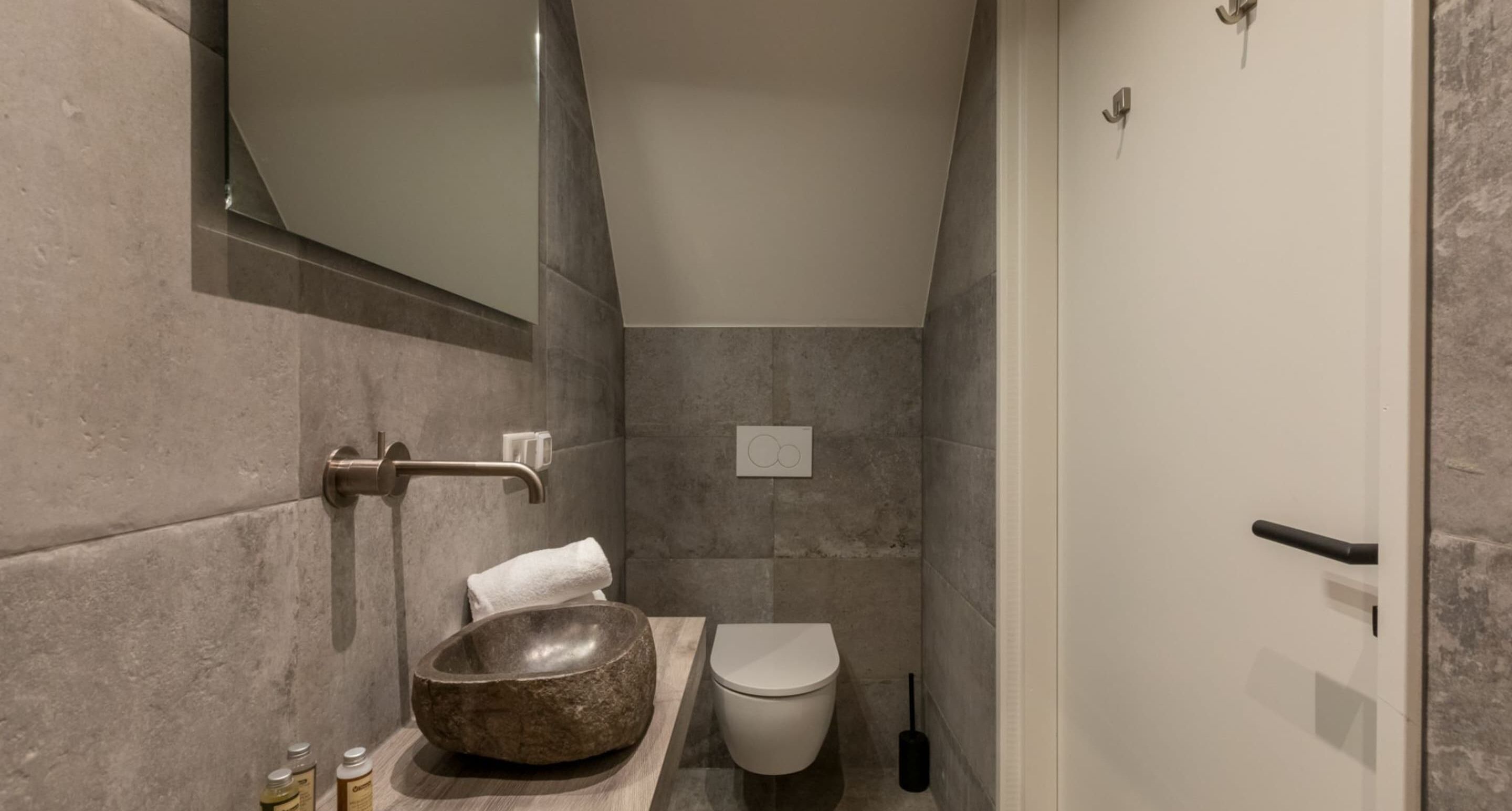 Une salle de bain avec un lavabo en pierre, des toilettes et une serviette accrochée au mur.