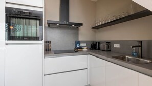 Uma cozinha moderna com forno embutido, pia de aço inoxidável e coifa.