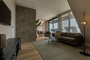Una sala de estar moderna con un sofá, una mesa de centro y un televisor sobre un mueble de madera.