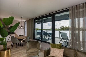 Una sala de estar moderna con un ventanal grande, un comedor y vistas al agua.