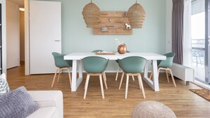 A modern dining area with a white table, green chairs, and a wooden wall decoration. - Holiday Home in Den Haag With Terrace (The Hague)
