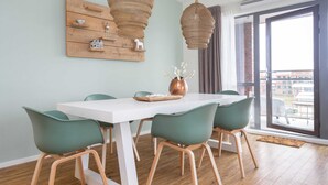 A dining area with a white table, green chairs, and a wooden floor. - Holiday Home in Den Haag With Terrace (The Hague)