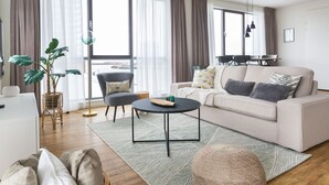 A modern living room with a sofa, coffee table, and a dining area with chairs. - Holiday Home in Den Haag With Terrace (The Hague)