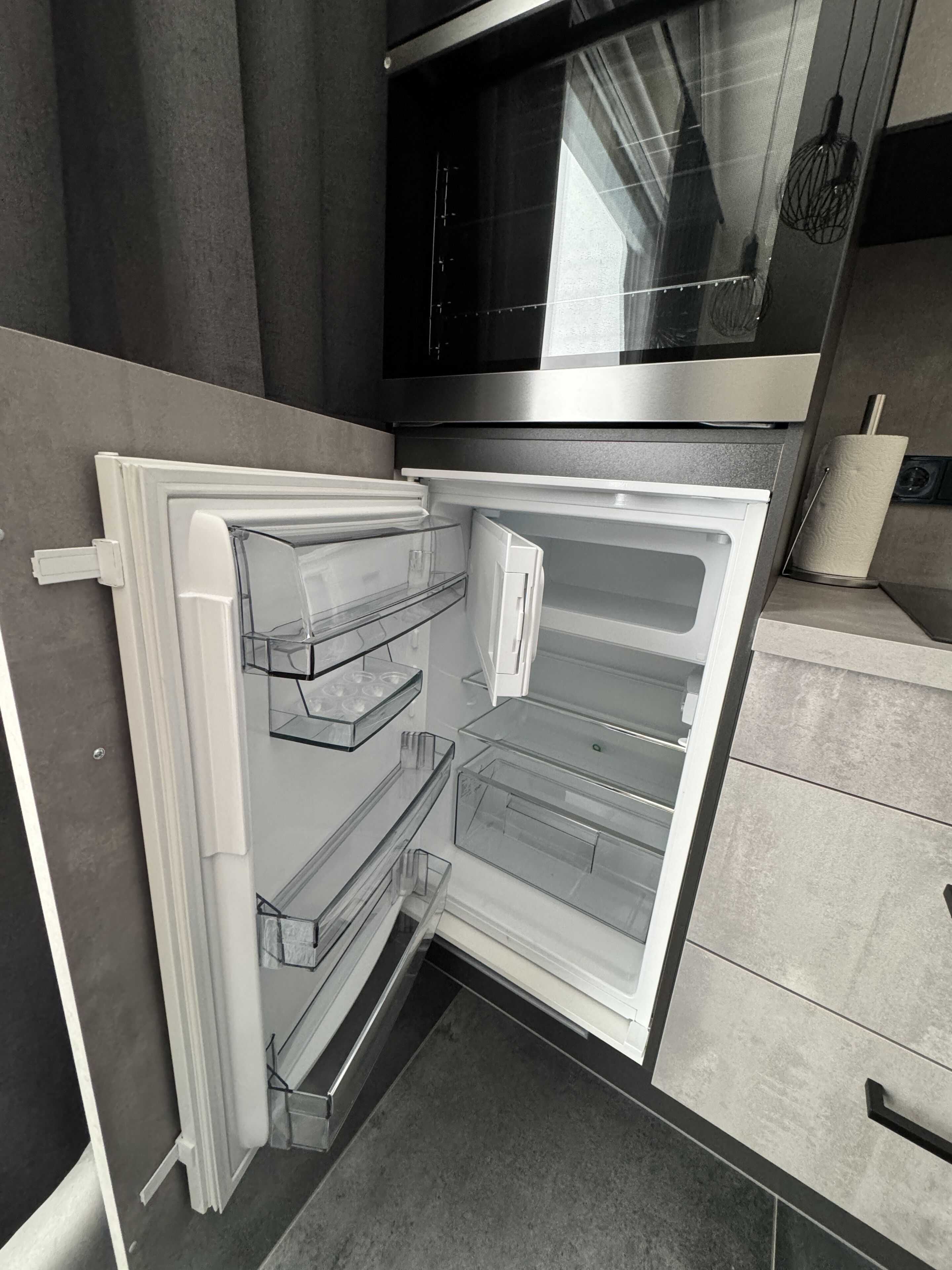 Una cocina moderna con un refrigerador empotrado, un microondas y un dispensador de toallas de papel.