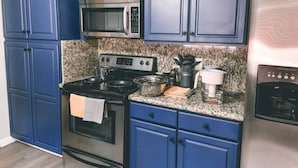 Une cuisine avec des meubles de couleur bleue, un four à micro-ondes en acier inoxydable, une cuisinière et un réfrigérateur.