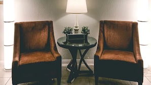 Deux fauteuils marron sont placés face à face, avec une petite table et une lampe entre eux.