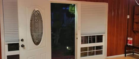 A wooden interior with a white door featuring a decorative glass panel and a small step leading outside.
