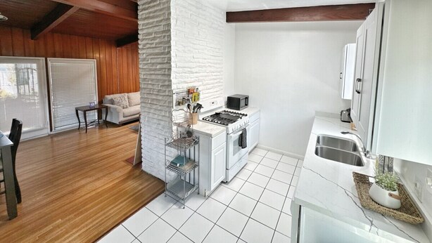 A compact kitchen with a stove, sink, and white cabinets. - MB Gem 2 - 1.3Miles To Beach, Close To LAX & Park (Manhattan Beach)