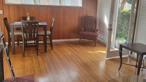 A dining area with a wooden table and chairs, a patterned armchair, and a glass table. - MB Gem 2 - 1.3Miles To Beach, Close To LAX & Park (Manhattan Beach)