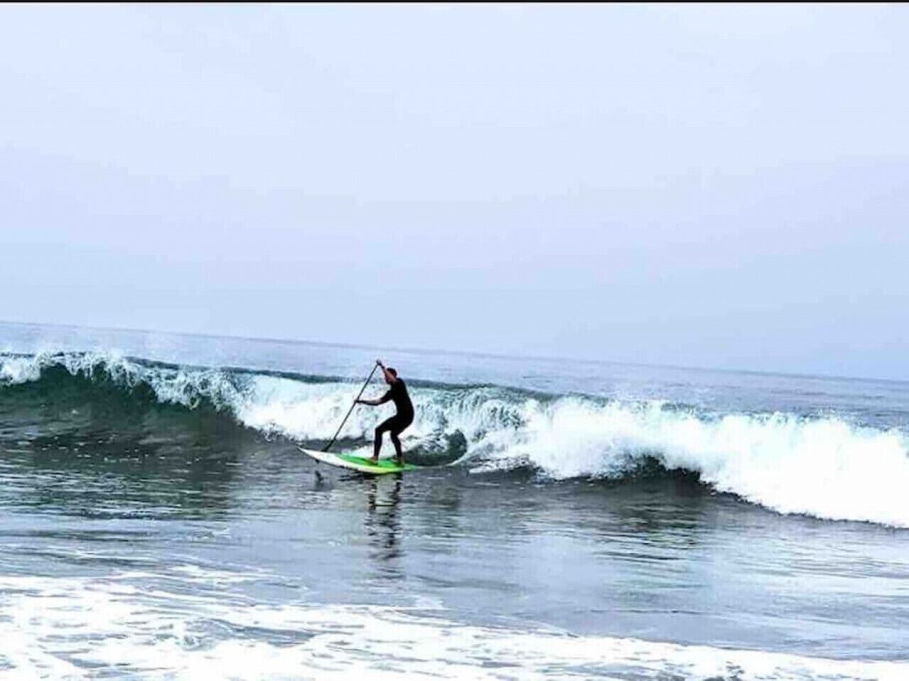 A person paddleboarding on a wave.
