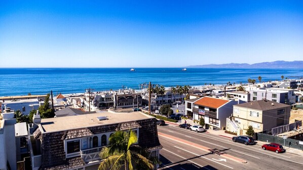 A coastal town with a clear view of the ocean, a road with cars, and buildings with various architectural styles. - MB Gem Lower - Steps To The Beach, Ocean Breeze (Manhattan Beach)