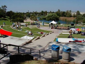 A park with a paved area, benches, and trash bins.