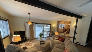 A living room with a sectional sofa, a television, and a dining area with a table and chairs. - Spacious Marquette Getaway  Trails Nearby  Perfect 4-Season Basecamp (Marquette)