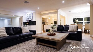 A modern living room with two black leather sofas, a wooden coffee table, and a patterned rug. - Devon Shores - Waterfront House (Clearwater)